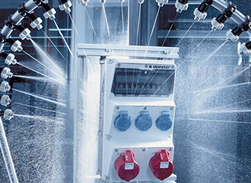 An AMAXX® receptacle combination by MENNEKES is sprayed with water in the test laboratory.