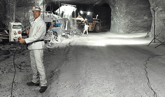 a man in a white suit stands in a salt mine holding an AMAXX combination unit