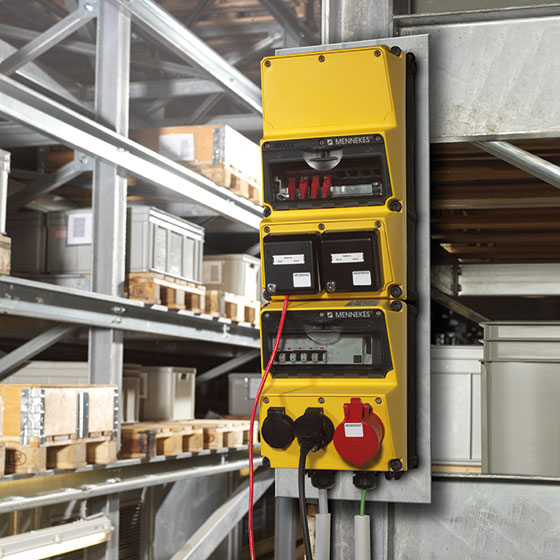 A yellow AMAXX combination unit on a wall, in the background a warehouse can be seen